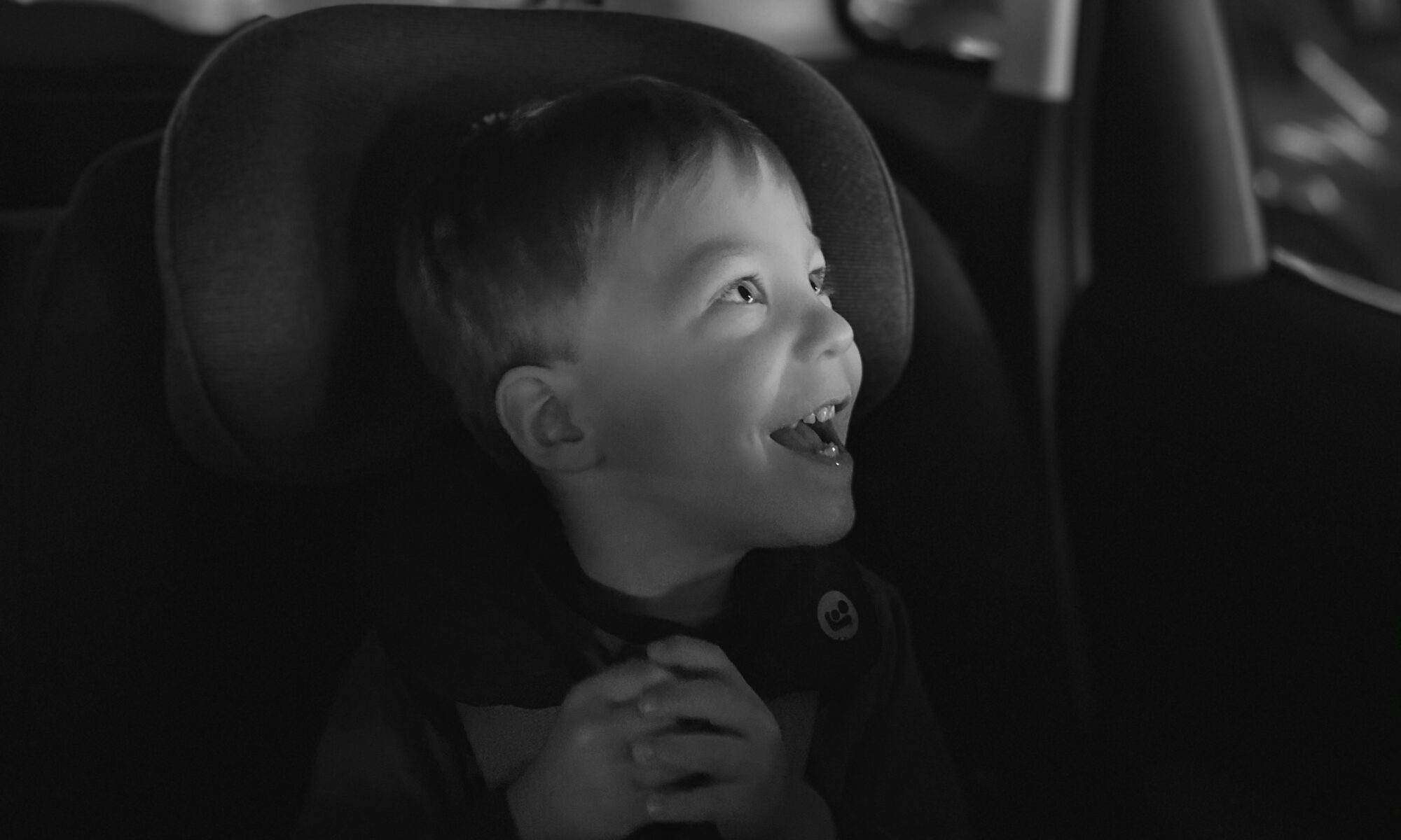 child sitting in car smiling